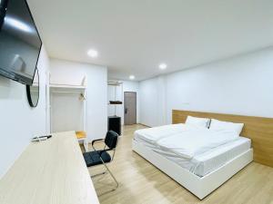 a bedroom with a white bed and a flat screen tv at PD Apartment Inn in Ban Pra Dok