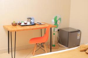 una mesa y una silla junto a una mesa pequeña y una TV en Acacia Hotel Mbarara en Mbarara
