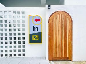 una puerta de madera y un cartel en la pared en PD Apartment Inn, en Ban Pra Dok