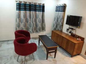 ein Wohnzimmer mit einem TV, einem Stuhl und einem Tisch in der Unterkunft Hotel HCB (Hemo Chandra Bhawan) in Brahmapur