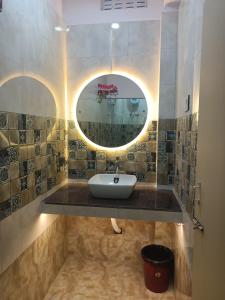 La salle de bains est pourvue d'un lavabo et d'un miroir rond. dans l'établissement Hotel HCB (Hemo Chandra Bhawan), à Brahmapur
