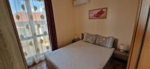 a small bedroom with a bed and a window at Luxury Apartments Ekaterina in Chernomorets