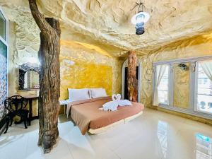 um quarto com uma cama grande numa parede de pedra em Yoko River Kwai Resort em Sai Yok