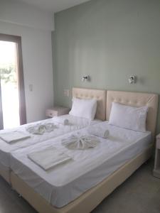 a large white bed with white sheets and pillows at Oasis in Parga
