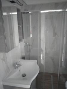 a white bathroom with a sink and a shower at Oasis in Parga