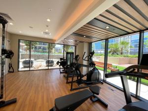 einen Fitnessraum mit Laufbändern und Crosstrainern in einem Zimmer mit Fenstern in der Unterkunft CitiHome- Business Bay in Dubai