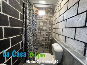 La salle de bains est pourvue de toilettes et d'un mur en briques. dans l'établissement Hostel La Casa Dilijan, à Dilidjan