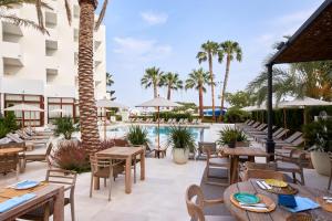 an outdoor patio with tables and chairs and a pool at Hotel Tres Torres in Santa Eularia des Riu