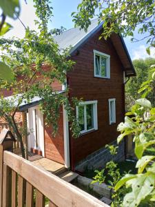 ein kleines Haus mit einem Holzzaun davor in der Unterkunft Карпатський котедж Karpatian cottage in Worochta