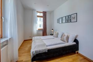 a bedroom with a bed with white sheets and a window at Kaza Guesthouse, centrally located 2 & 3 bedroom Apartments in Augsburg in Augsburg