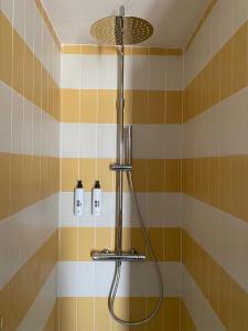 a shower in a bathroom with yellow and orange tiles at Hotel SALEI in Ghigo