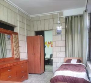 a bedroom with a bed and a dresser and a mirror at Yalla Hostel in Ramallah