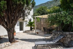 a patio with a bench and a table and trees at Holiday Home Zaton in Dubrovnik