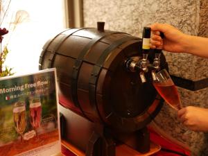 una persona que vierte una copa de vino en un barril de vino en The BREAKFAST HOTEL Fukuoka Tenjin en Fukuoka