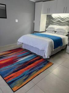 1 dormitorio con 1 cama con una alfombra colorida en el suelo en Cozy Cottage, en Brakpan