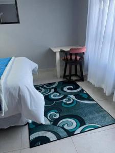 Un dormitorio con una cama y una silla y una alfombra. en Cozy Cottage, en Brakpan 6 fotos más