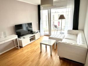 a living room with a white couch and a flat screen tv at Cape Homes St-Sulpice in Saint-Sulpice