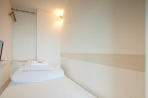 a bedroom with two beds and a light on the wall at Drop Inn Tottori in Tottori