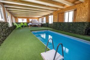 uma casa com piscina com mesa e cadeiras em בקתות עץ מעל העננים - אירוח דרוזי - בקתות כפריות עם נוף מהמם ובריכה מחוממת מקורה משותפת em Beit Jann