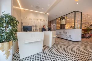 a woman standing at a counter in a store at Hotel Amsterdam De Roode Leeuw in Amsterdam