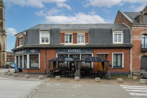 a hotel with tables and umbrellas in front of it at L'abbatiale in Corbie