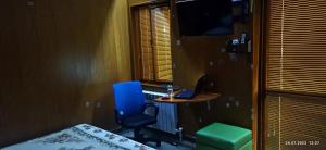 アルマトイにあるApartment in a guest houseのデスク、青い椅子、ノートパソコンが備わる客室です。