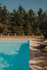 a blue swimming pool with trees in the background at Trulli del Carmine in Martina Franca