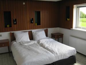 um quarto com uma cama com lençóis brancos e almofadas em vakantiehuis Warder em Warder