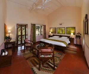瑞诗凯诗Neemrana's Glasshouse on the Ganges的一间卧室，配有一张床、一张桌子和几把椅子