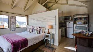 a bedroom with a bed and a refrigerator and a table at The Ark Guesthouse at Marina Martinique in Jeffreys Bay