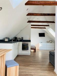 cocina y sala de estar con paredes blancas y suelo de madera. en MariaDora, en Alter Graben
