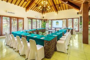 una sala de conferencias con una mesa larga y sillas blancas en Risata Bali Resort & Spa en Kuta