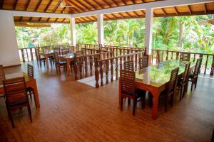 a restaurant with wooden tables and chairs and trees at Rockery Villa Ayurveda in Bentota