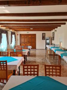 a dining room with tables and chairs and wooden ceilings at Tőrös Panzió in Szabolcs