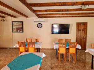 a dining room with tables and chairs and a flat screen tv at Tőrös Panzió in Szabolcs