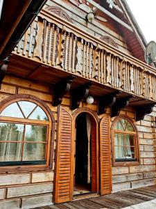 a wooden house with a balcony on top of it at Dom Wypoczynkowy Windmill in Kopalino