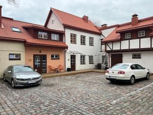 two cars parked in a parking lot in front of two houses at B2 Apartments in Klaipėda