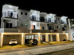 a large white building with two cars parked in front of it at Bora Lindi Ulcinj apartments in Ulcinj