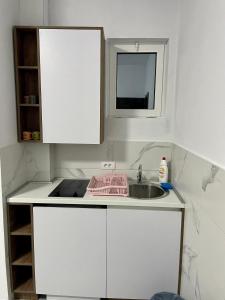 a white kitchen with a sink and a window at Lindi apartments in Ulcinj