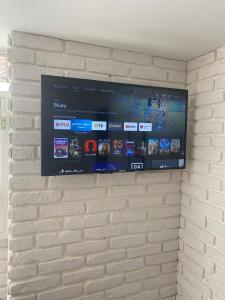 Un televisor de pantalla plana colgado en una pared de ladrillos en Everest Grao y Playa de Gandia, en Gandía