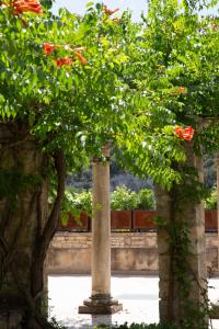 una columna y dos árboles con flores rojas en Prieuré Saint-Nicolas - Les Maisons en Blauzac