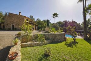 a house with a stone wall and a yard at Cocons in Sineu