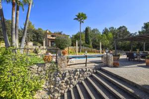 a swimming pool with a stone wall and a resort at Cocons in Sineu