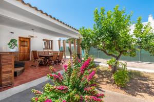 una casa con un patio con un árbol y flores rosas en La Bombonera en Catadau