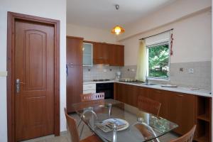 a kitchen with a glass table and wooden cabinets at Orizzonte Apartments Lefkada in Lefkada