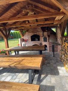 a patio with wooden benches and a stone fireplace at Rajski Zakątek in Chłopy