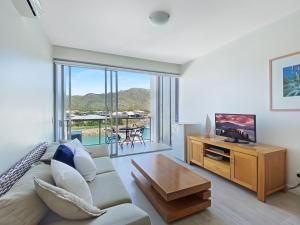 ein Wohnzimmer mit einem Sofa und einem TV in der Unterkunft Blue on Blue Studio Room 1322 in Nelly Bay