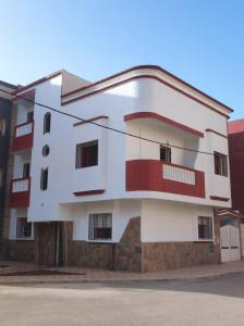 un edificio blanco con balcones rojos en una calle en Dar Pikhasa, en Saidia 