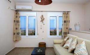 a living room with a couch and two windows at Orizzonte Apartments Lefkada in Lefkada