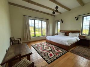 a bedroom with a bed and a table and windows at Naivasha 4-Bedroom All Ensuite Cottage in Naivasha